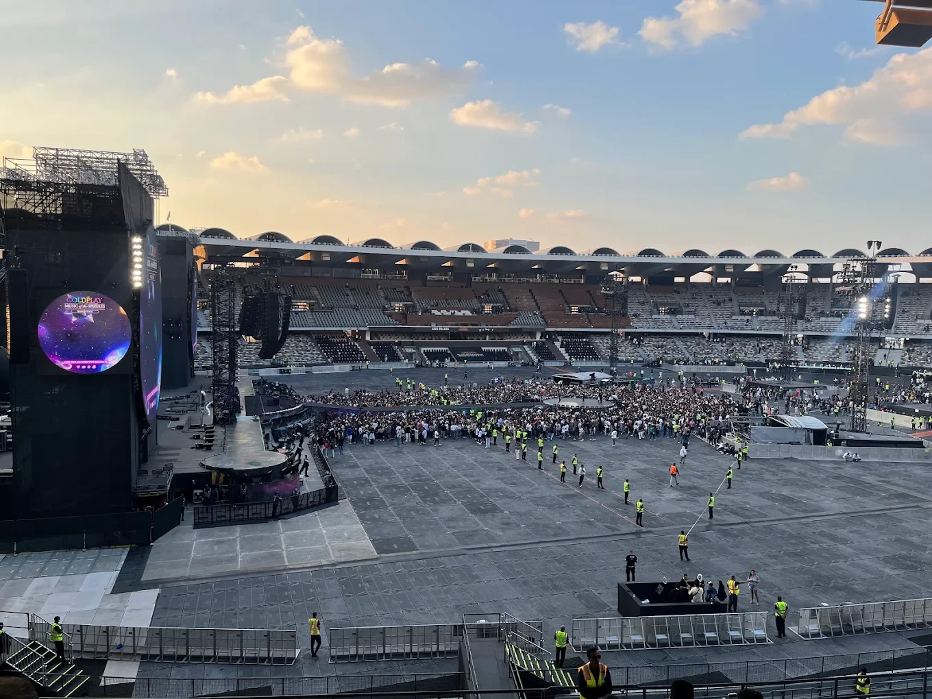 Concert setup at Zayed Sports City, Abu Dhabi, with crowd gathering.